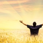 Man in field with hands lifted to God