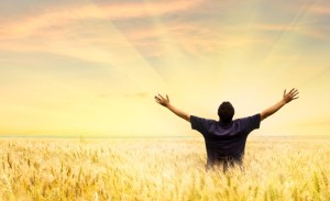 Man in field with hands lifted to God 